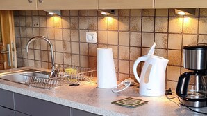 A kitchen with wooden cabinets, a stainless steel sink, and a tiled backsplash. - Farm❤ (Eppan)