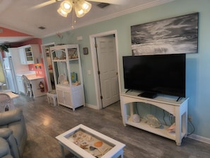 A living room with a television, a fish tank, and a dining area with a chair and table.