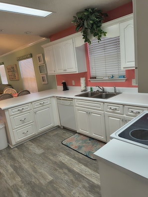 A kitchen with white cabinets, a dishwasher, a sink, and a window with blinds. - Venture Out, #402 North Marlin Dr. New amenities, WITH GOLF CART! (Panama City)