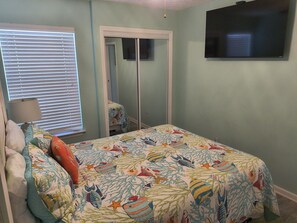 A bedroom with a bed, a television, and a closet.