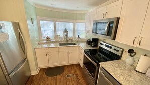 A compact kitchen with white cabinets, a stainless steel refrigerator, a microwave, and a stove. - Venture Out, #646 Octopus Dr. Comes WITH GOLF CART! (Panama City)