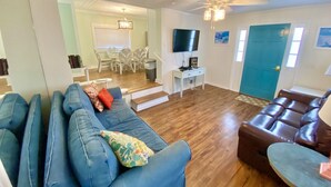 A living room with a blue sofa, a brown leather couch, and a television on the wall. - Venture Out, #646 Octopus Dr. Comes WITH GOLF CART! (Panama City)