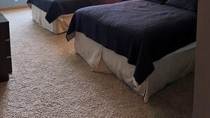 Un dormitorio con dos camas, ventilador de techo, ventana y lámpara.