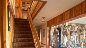 A wooden staircase leading to a stone wall with a fireplace. - Spring Creek Guest House (Ennis)