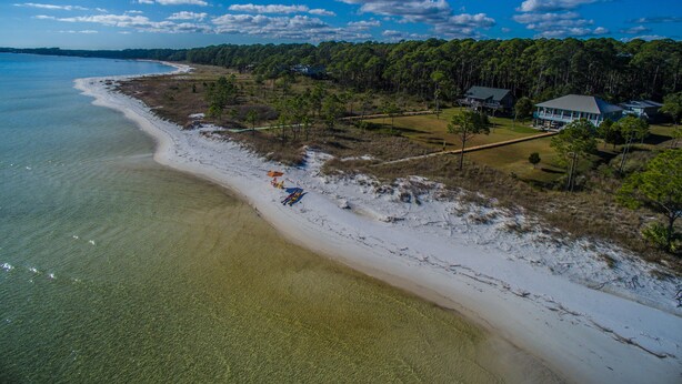 Una propiedad costera con playa, una casa grande y una zona boscosa.