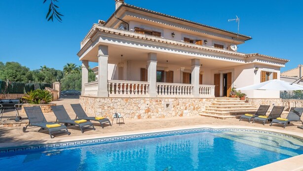 A two-story villa with a swimming pool, outdoor seating, and a stone wall. - Charming Villa Can Albons in Porto Colom for 8 people (Portocolom)