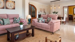 A living room with two sofas, a coffee table, and a dining area with a table and chairs. - Charming Villa Can Albons in Porto Colom for 8 people (Portocolom)