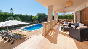 A covered outdoor area with a pool, lounge chairs, and a seating area with tables and cushions. - Charming Villa Can Albons in Porto Colom for 8 people (Portocolom)