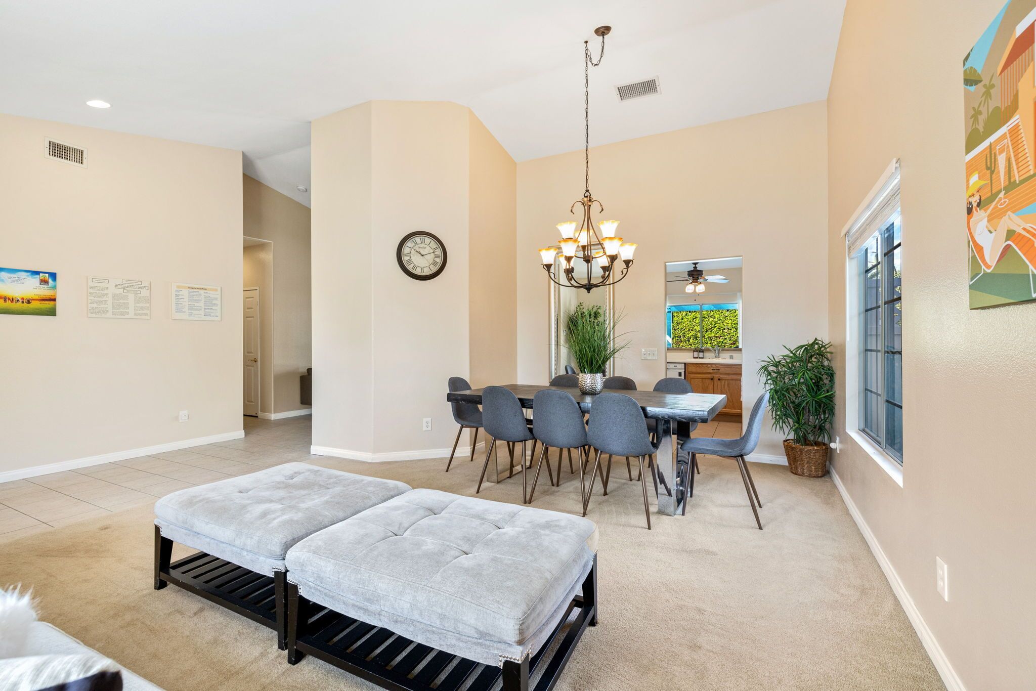 A spacious room with a dining area, a chandelier, and a large window.