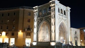 A historic building with ornate arches and columns, featuring a large central archway. - Central Plaza (Lecce)