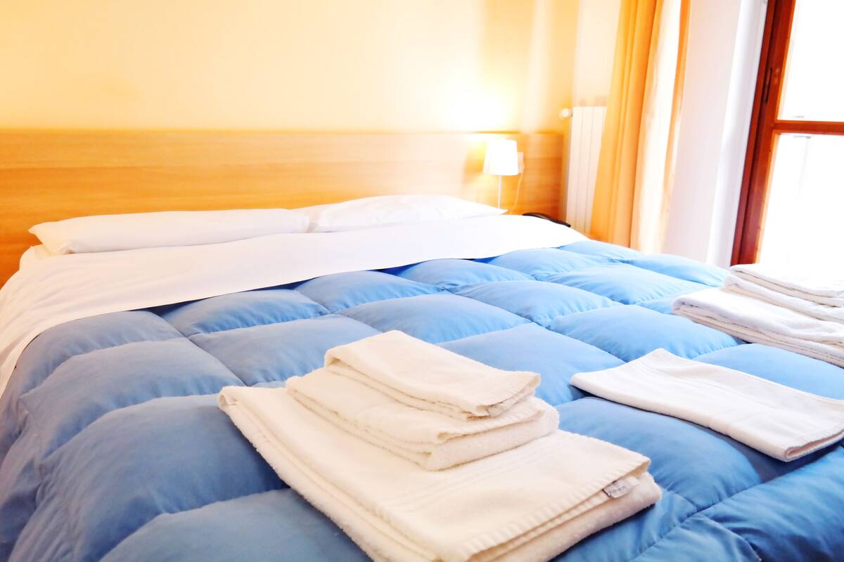 Ein Hotelzimmer mit einem Bett, blauer Bettwäsche, weißen Kissen und gefalteten Handtüchern.