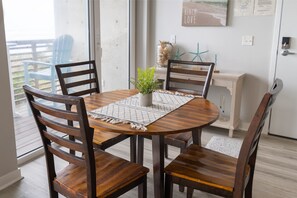 A round wooden dining table with four chairs, a small potted plant, and a decorative rug. - Bright Oceanfront Oasis ~ Stunning Views ~ Beach! (Rockaway Beach)