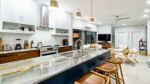 Una cucina moderna con un piano di lavoro in marmo, elettrodomestici in acciaio inossidabile e luci a sospensione.