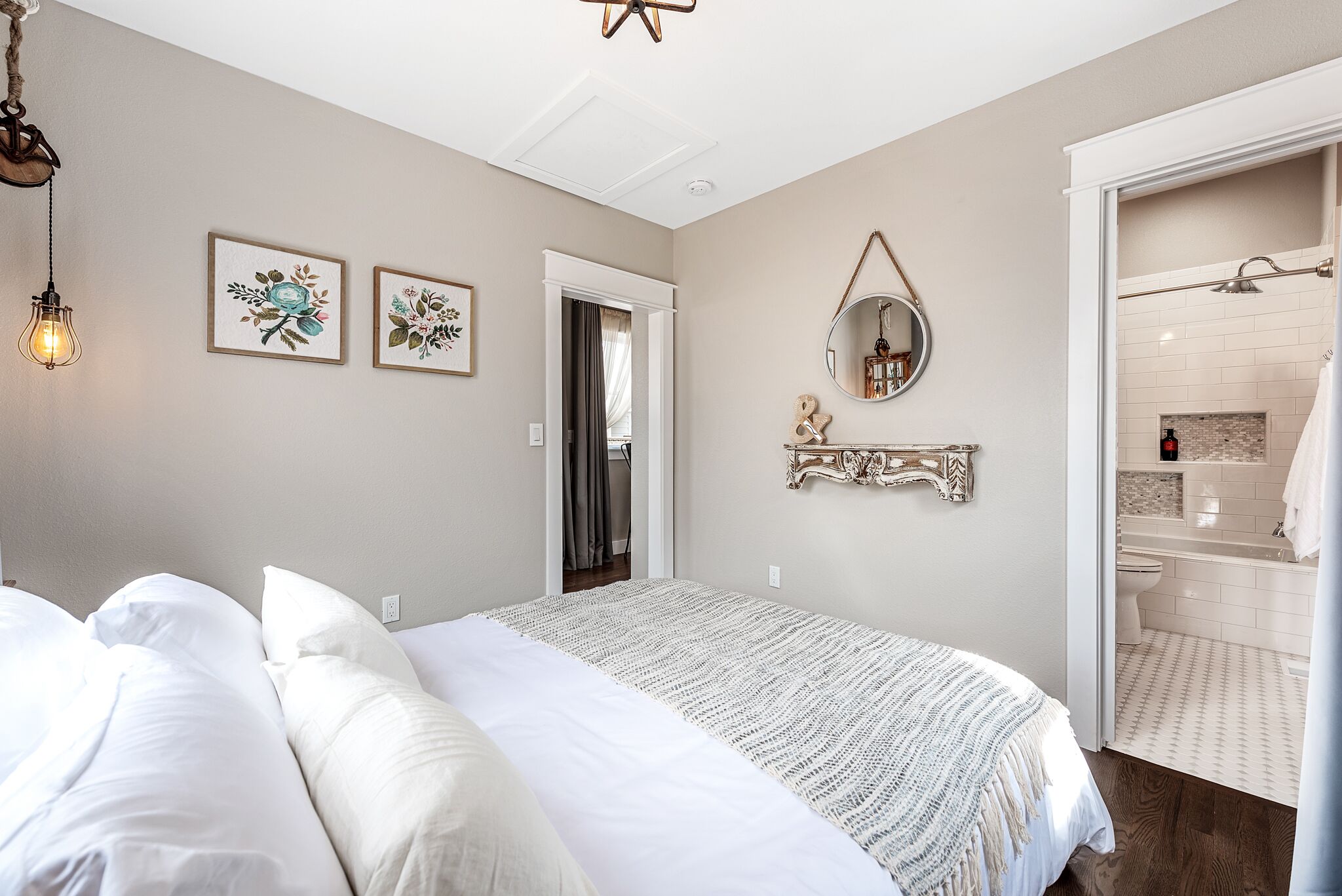 A bedroom with a large bed, a bedside table, a mirror, and a door leading to a bathroom.