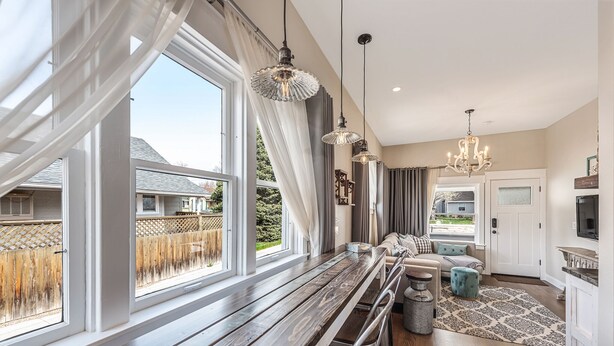A modern kitchen with a wooden countertop, hanging pendant lights, and a view of the backyard through large windows. - Agatha Stecker cottage - Historic Miner’s cottage (Louisville)