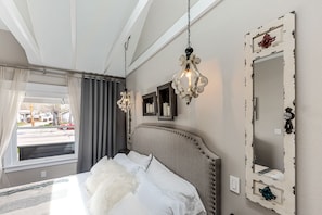 Un dormitorio con una cama, un espejo grande y dos lámparas colgantes.