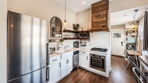 A modern kitchen with stainless steel appliances, wooden accents, and a dining area with a wooden table and chairs. - Agatha Stecker cottage - Historic Miner’s cottage (Louisville)