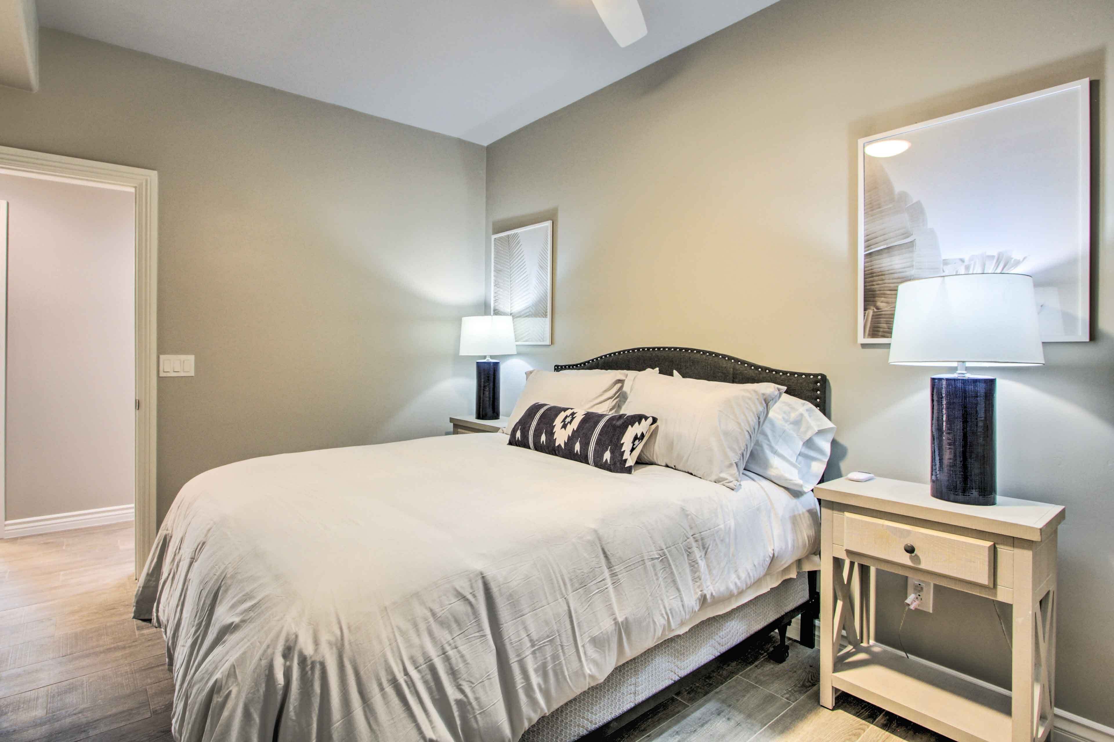 Un dormitorio con cama, mesitas de noche y decoración en la pared.