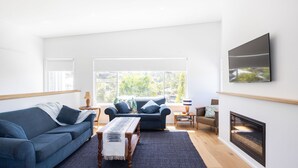 Una sala de estar moderna con un sofá azul, un sillón a juego, una mesa de centro y una chimenea.