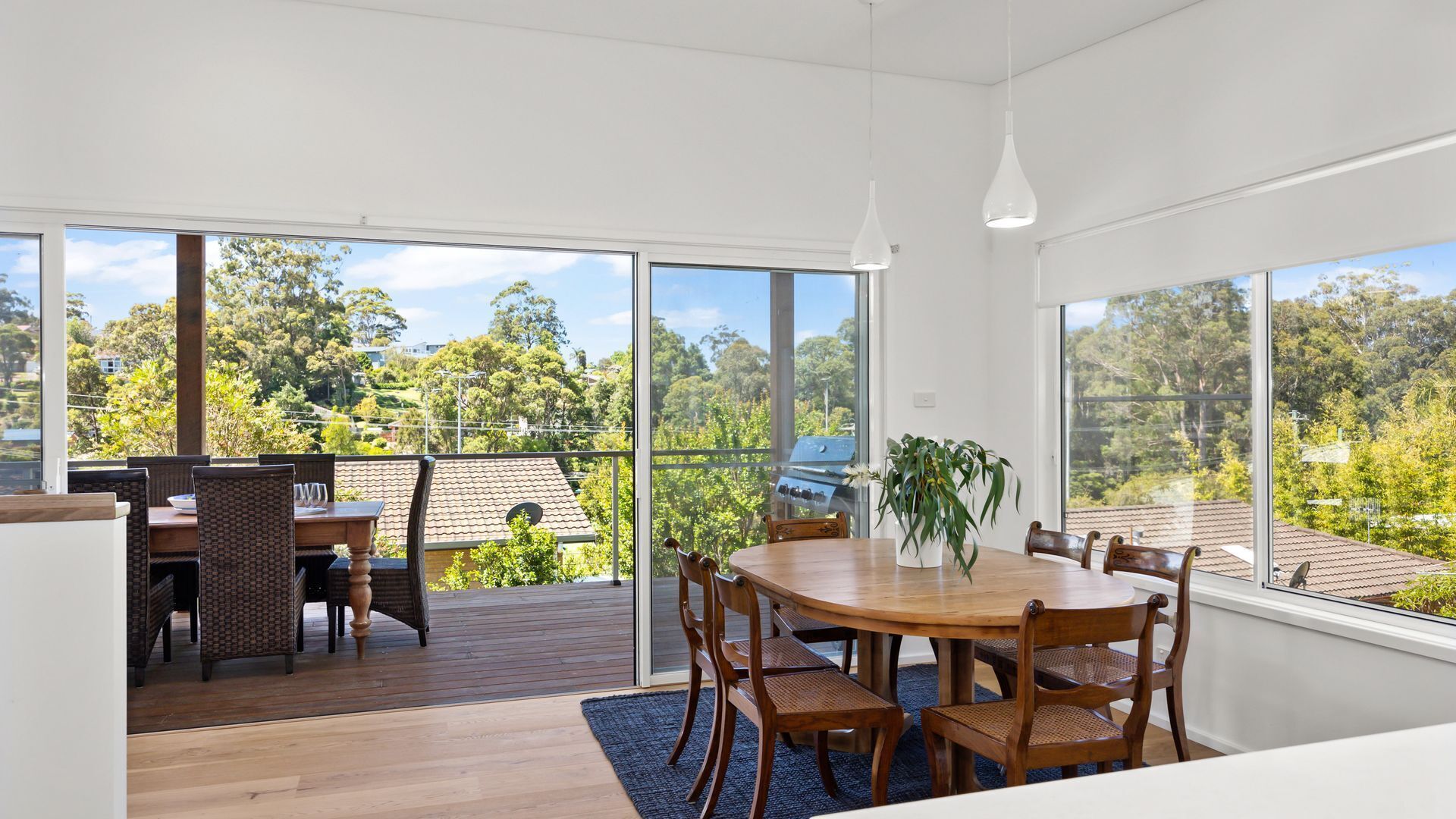 Un comedor moderno con una mesa grande y sillas, ventanas amplias que ofrecen vistas a un paisaje exuberante.
