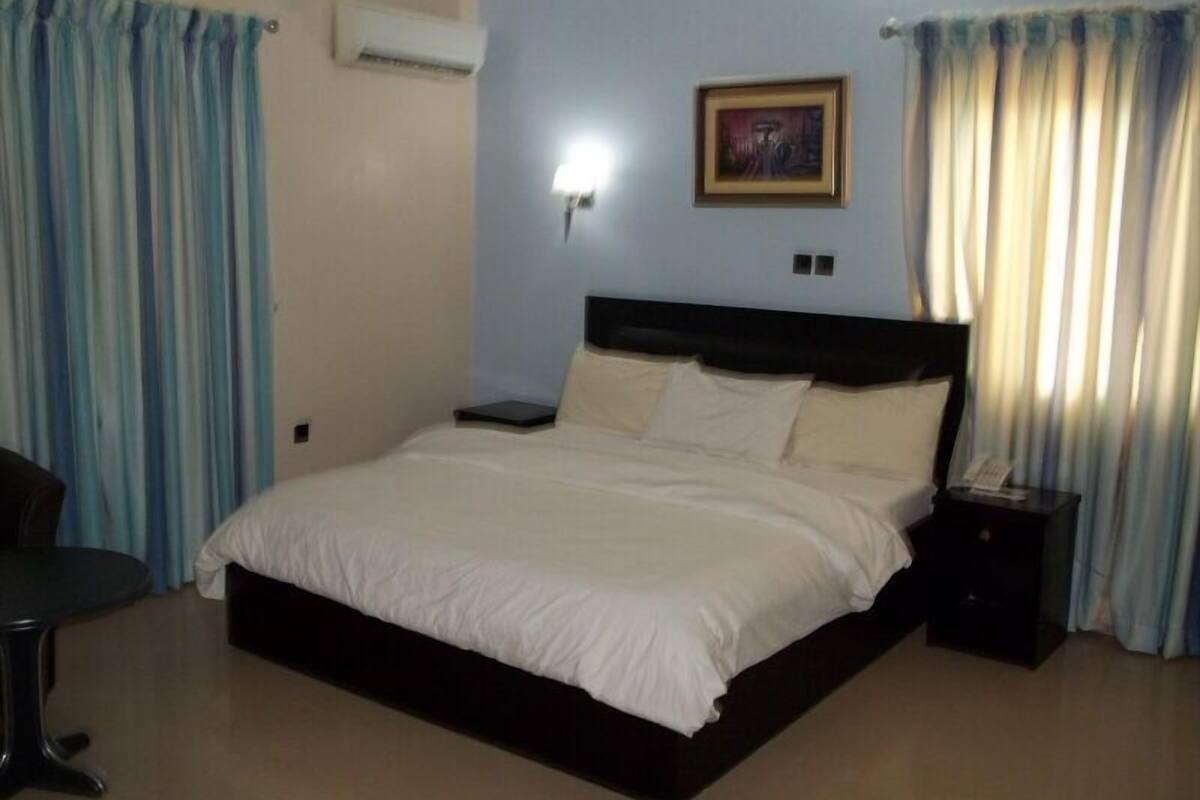 A bedroom with a bed, bedside table, and a wall-mounted air conditioner.