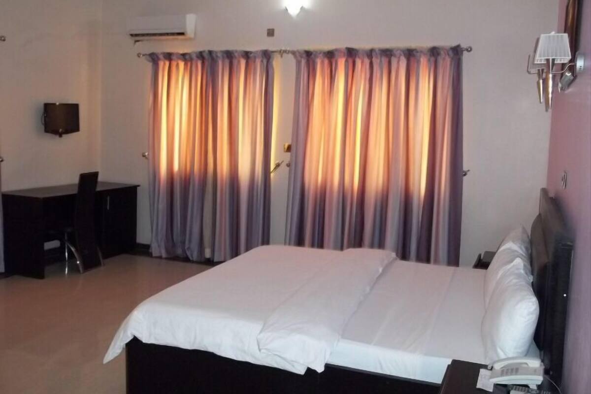 A hotel room with a bed, a desk, and a chair.