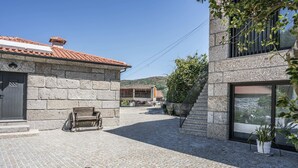 A courtyard with stone buildings, a wooden bench, and potted plants. - Porch House (Braga)