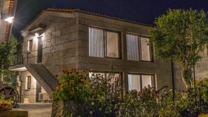 A stone building with a staircase, large windows, and a garden with flowers. - Porch House (Braga)