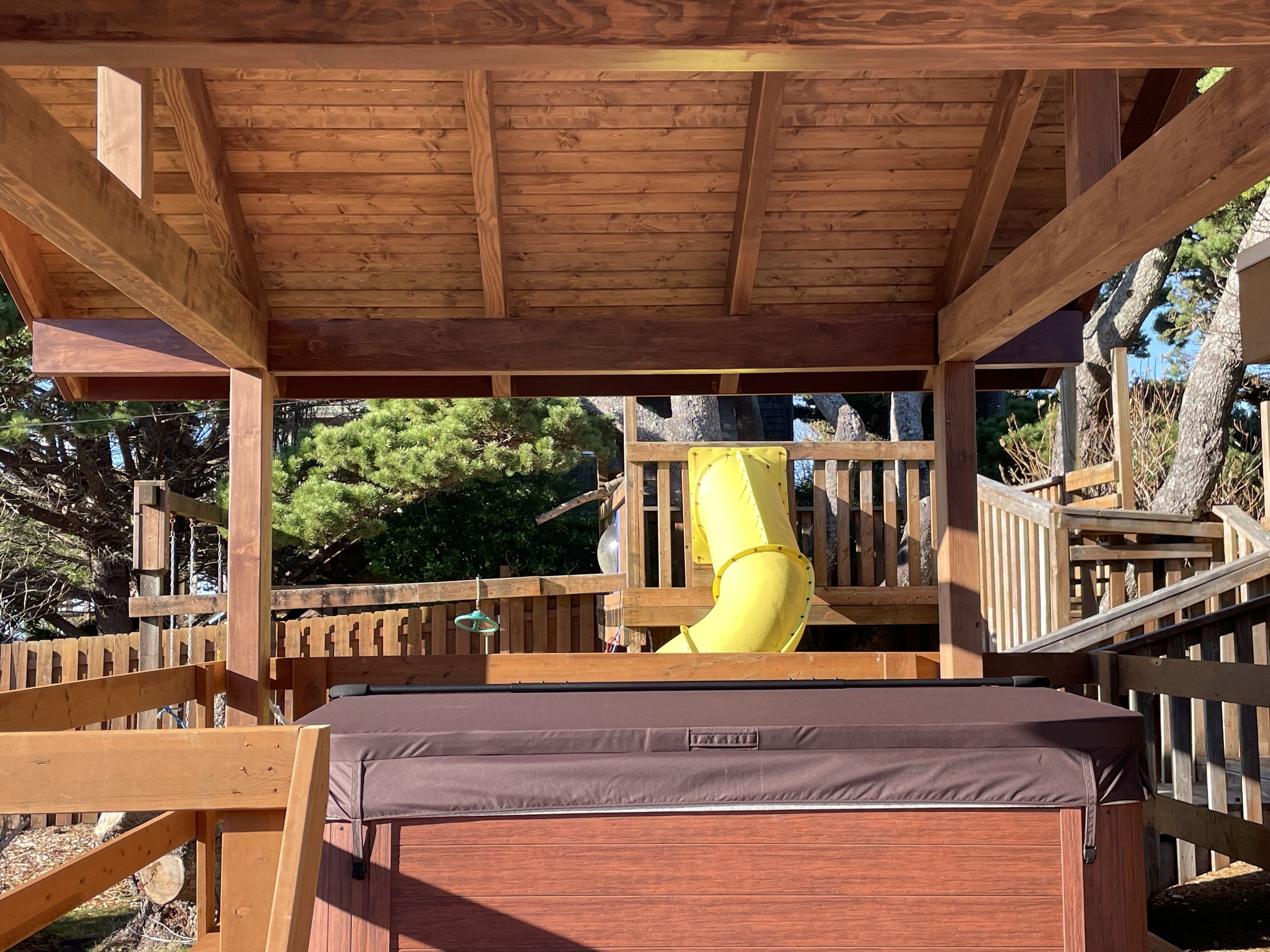 Une terrasse en bois avec un toboggan jaune et un banc.