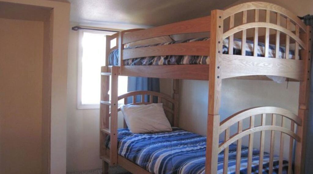 A bunk bed with a wooden frame and a blue striped bedspread.
