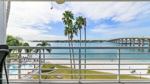 Ein Balkon mit Blick auf einen Strand, Palmen und eine Brücke.