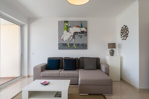 A modern living room with a sectional sofa, a coffee table, and a painting on the wall.