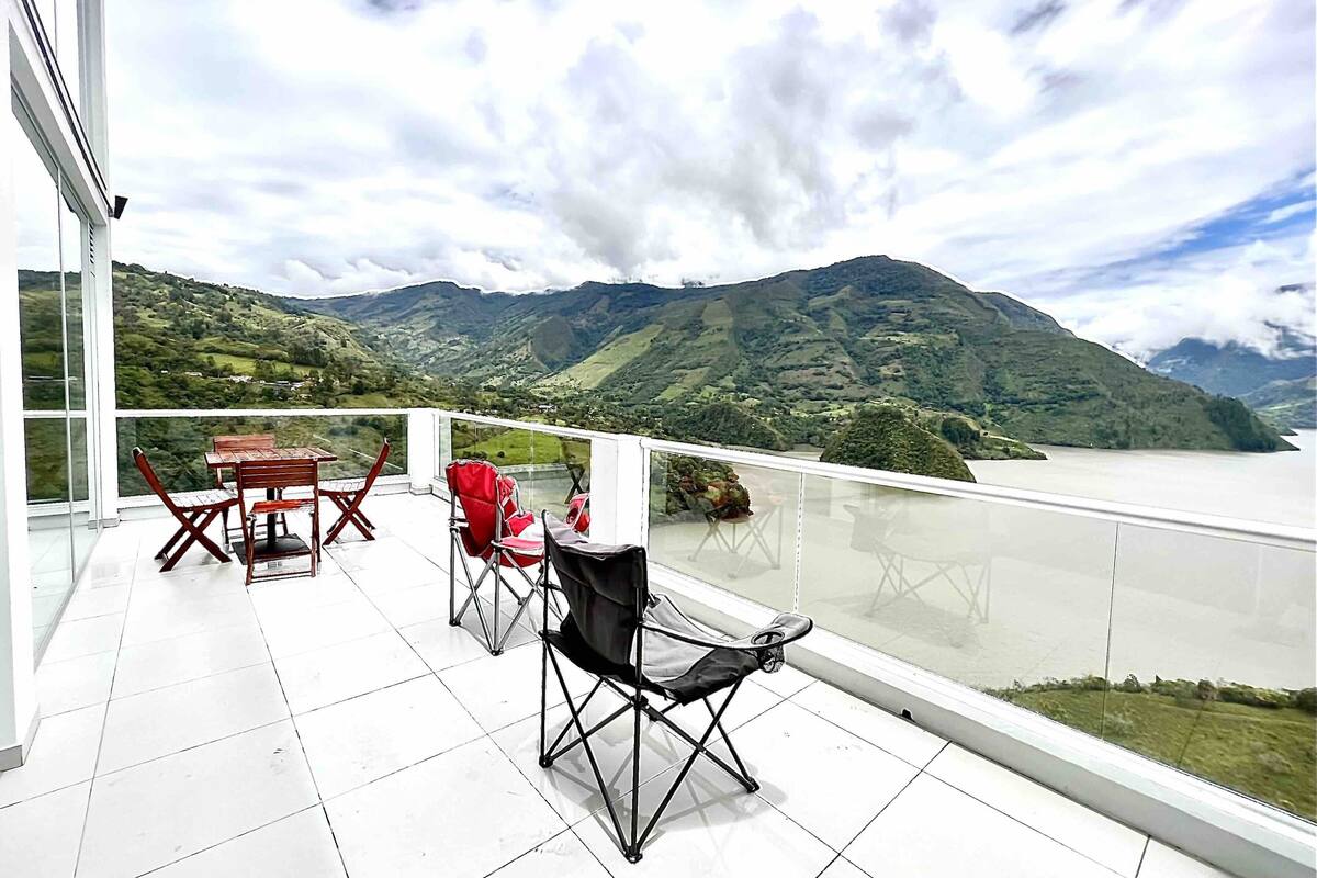 A balcony with a table and chairs overlooking a mountainous landscape.
