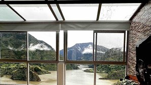 Un dormitorio con un ventanal que ofrece vistas a un río y montañas.