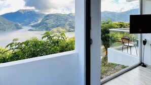 Un balcón moderno con vista a un lago y montañas.