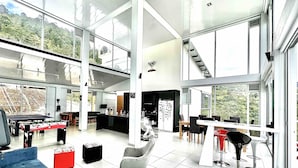 Un interior amplio y moderno con techos altos y ventanas grandes que ofrecen vistas de un paisaje montañoso.