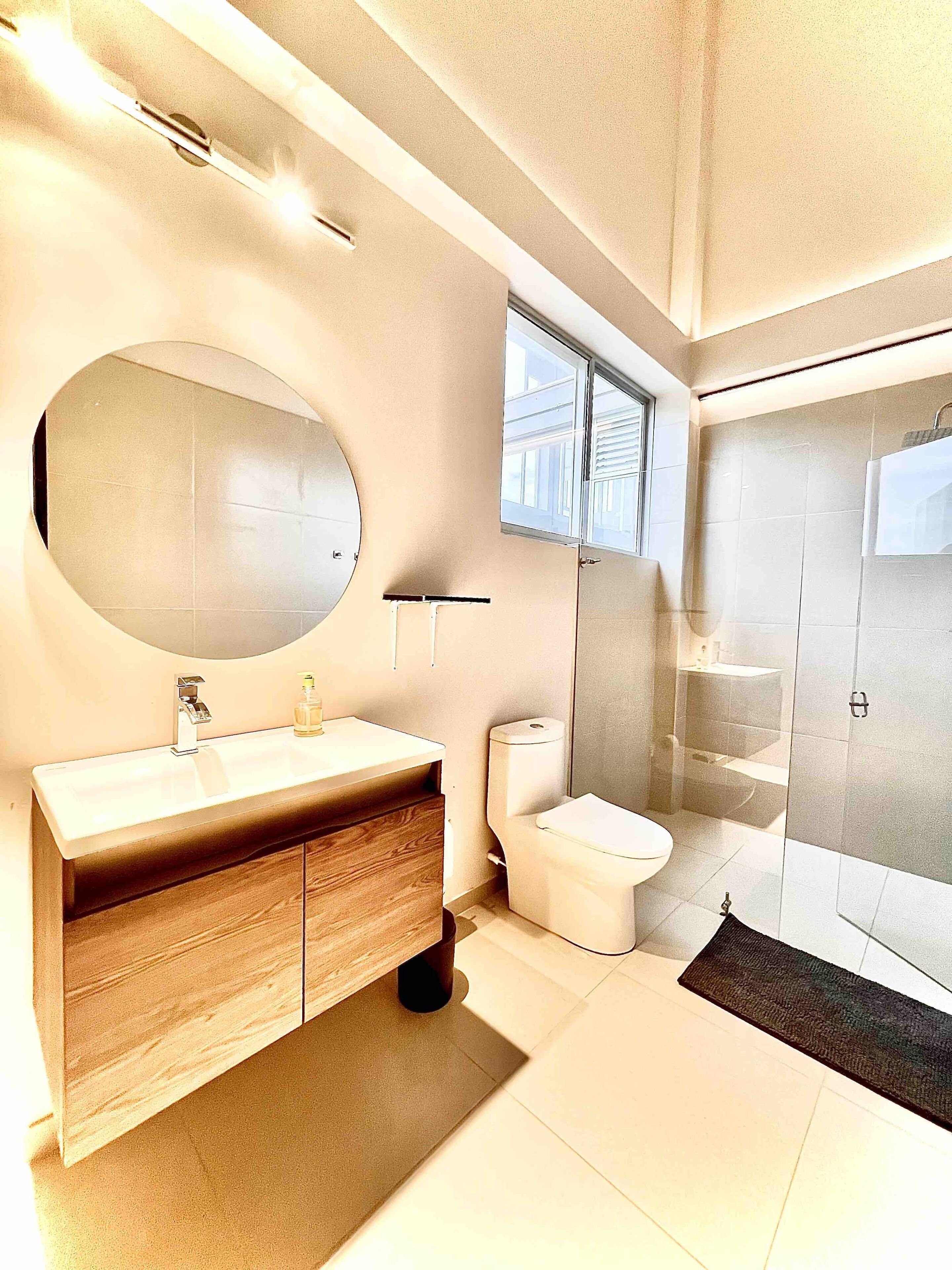 Une salle de bain moderne avec un grand miroir, un meuble-lavabo en bois, des toilettes et une douche à l’italienne.