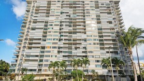 Un grand hôtel à plusieurs étages, doté de balcons à chaque niveau, entouré de palmiers et de verdure.