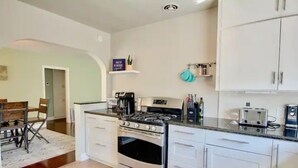 Una cucina con mobili bianchi, un fornello a gas, una macchina da caffè e un tostapane.