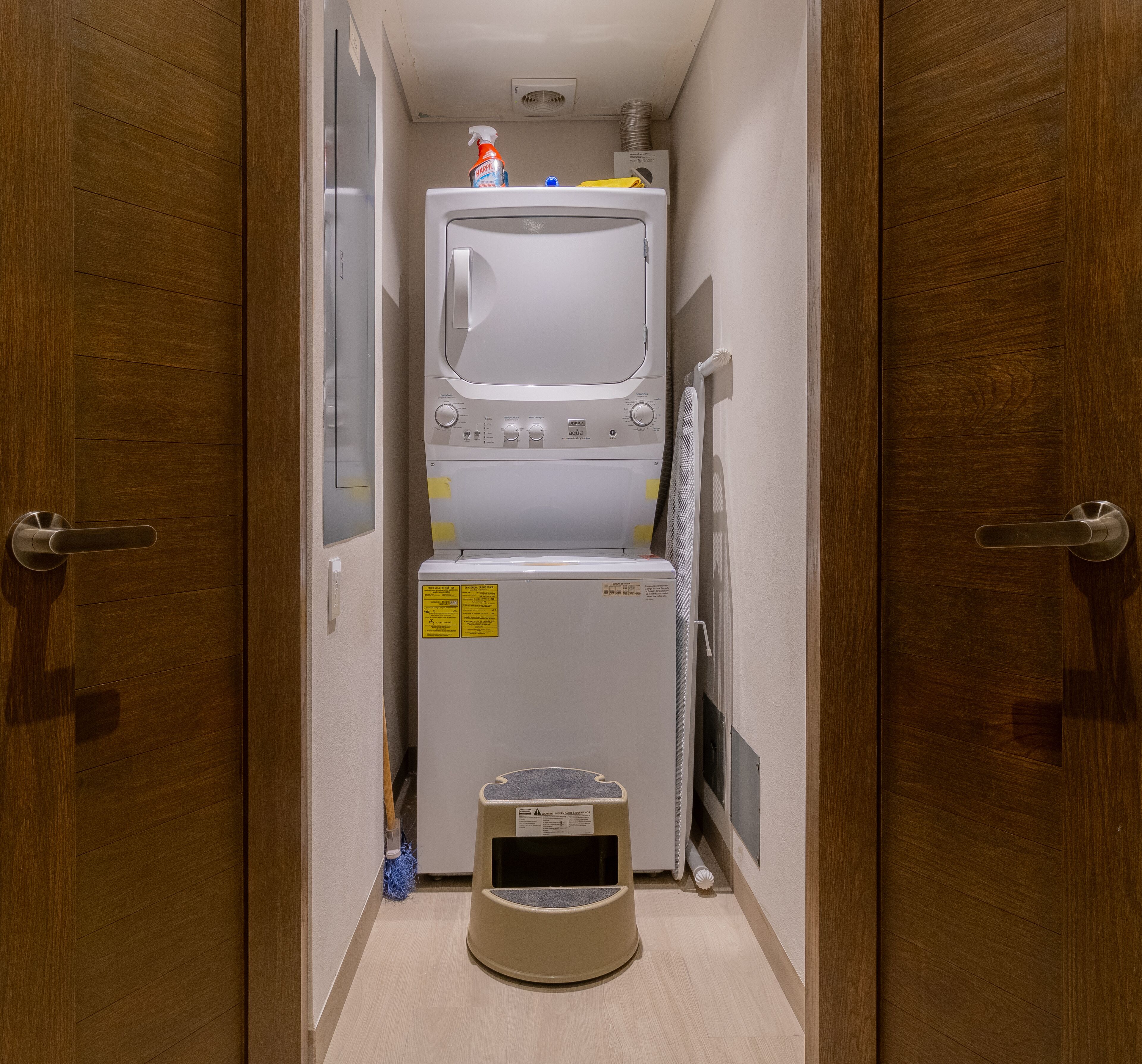 A compact laundry room with a washing machine, dryer, and a pet bed.