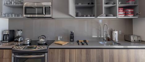 Uma cozinha moderna com eletrodomésticos embutidos, bancada de madeira e forno de aço inoxidável.