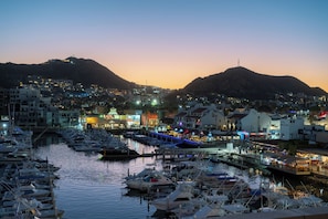 Un port de plaisance avec des bateaux amarrés, un pont qui relie la ville, et des bâtiments dotés d’enseignes lumineuses.