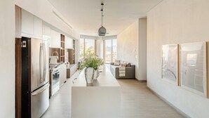 Eine moderne Küche mit integrierten Geräten, einer Kochinsel und einem großen Fenster mit Blick auf die Stadt.