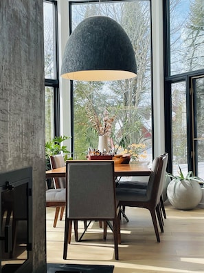 Uma área de jantar moderna com uma mesa grande, cadeiras e um lustre.