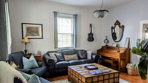 Una sala de estar con un sofá, una mesa de centro de madera, un piano y una guitarra.