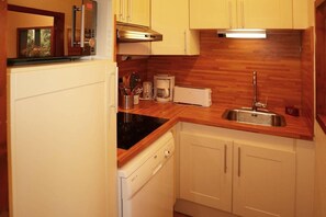 A compact kitchen with a built-in dishwasher, a toaster, and a sink.