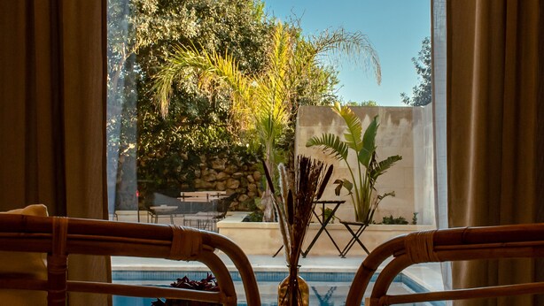 Habitació amb dues cadires de vimetra davant d'una finestra que donava a una piscina i un jardí.