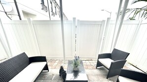 Un'area patio con mobili da esterno, un tavolo e una recinzione bianca.
