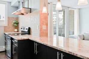 Una cocina con encimera de granito, armarios negros, campana de acero inoxidable y un amplio ventanal con vistas.