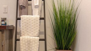A bathroom with a towel rack, a potted plant, and a wooden cabinet.